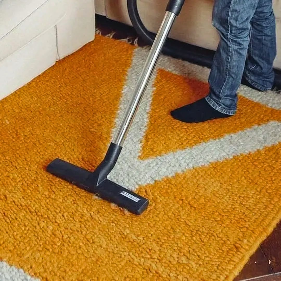 Vacuuming an orange geometric area rug