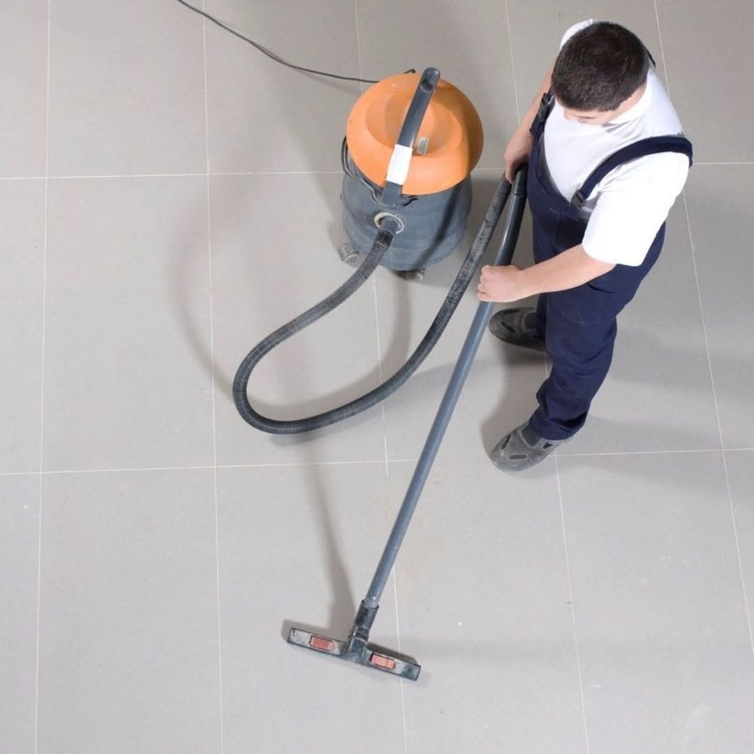 Worker vacuuming a large commercial tile floor