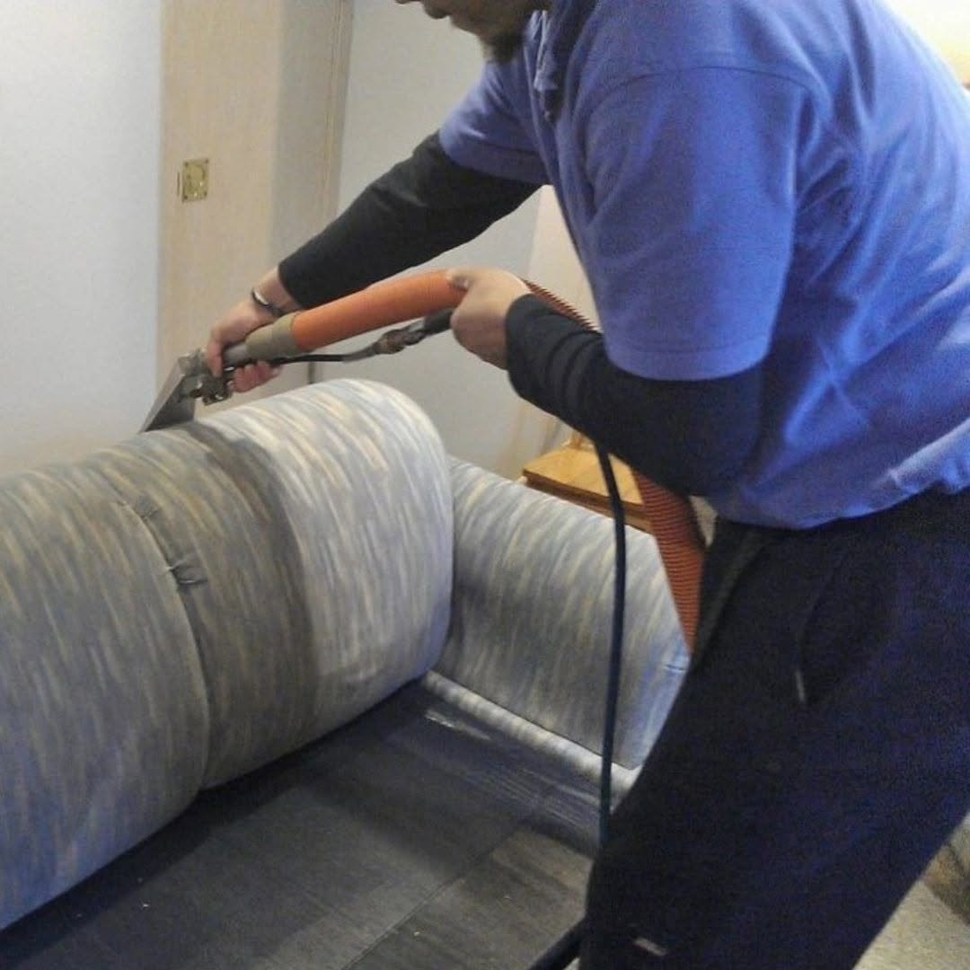 Technician cleaning a striped sofa with an upholstery tool