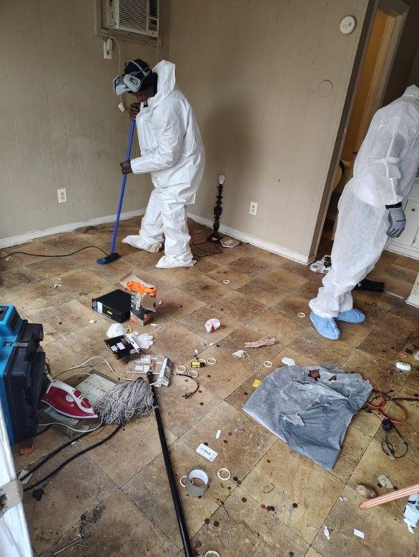 Restoration crew in protective gear cleaning a water-damaged room