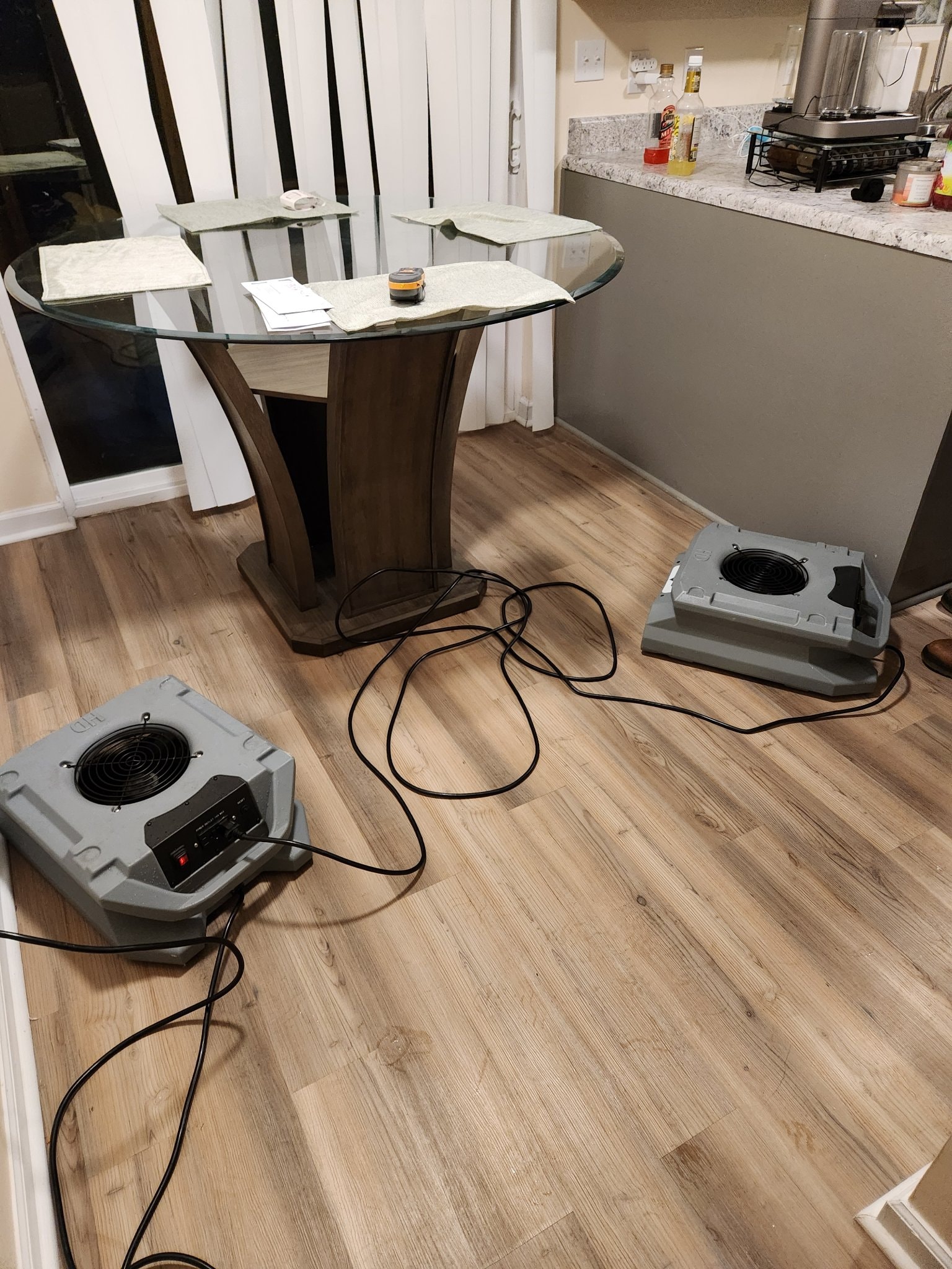 Air movers drying a dining room floor after water damage